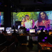 Produzent:innen sitzen vor einer Vielzahl an Bildschirme vor eine Großen Leinwand im Rahmen der Produktion der Most Wanted: Music Konferenz 2020